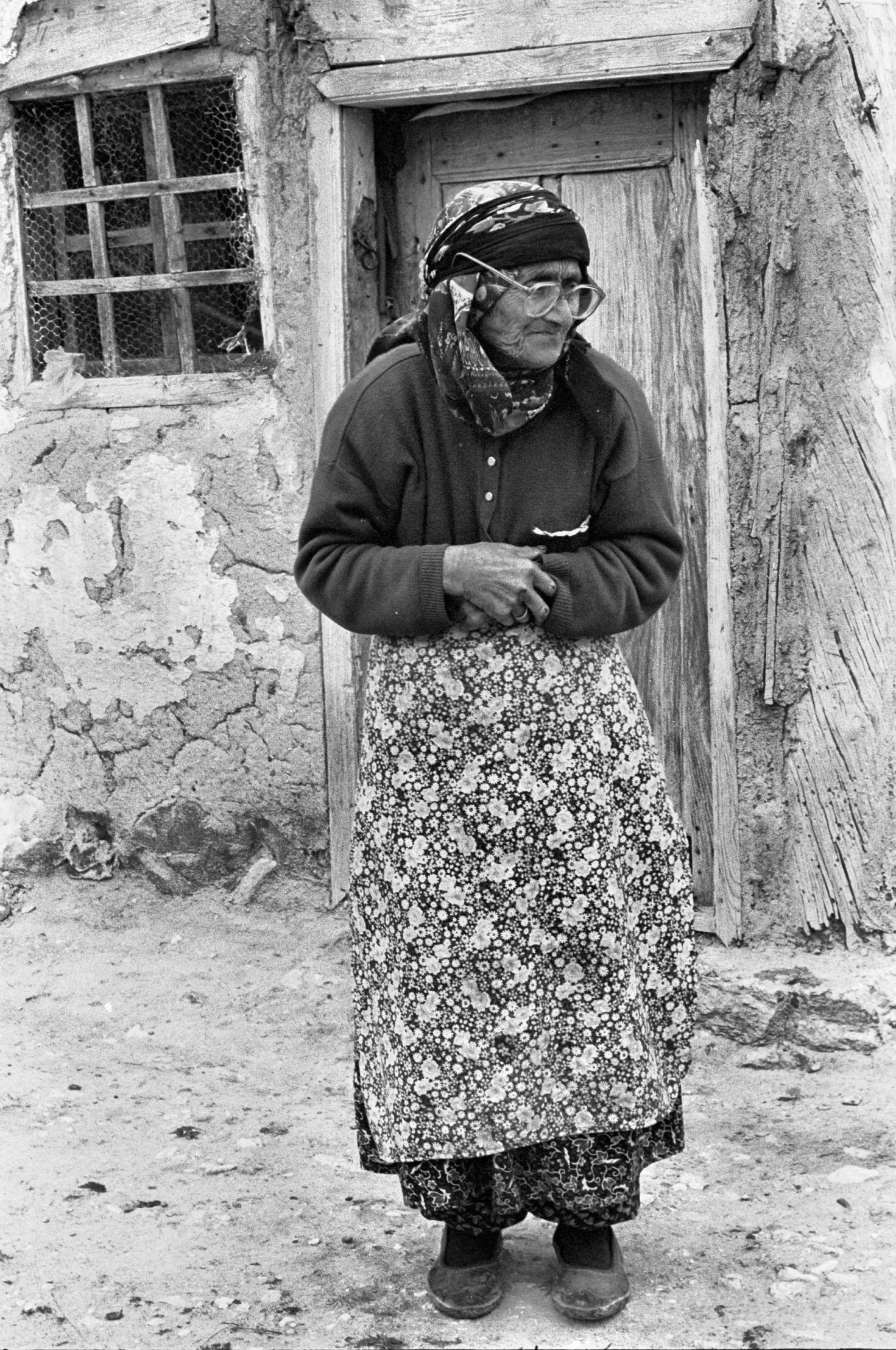 Imagine several Muslim women sitting cross-legged on a floor, stitching embroidery and watching a music video liberally spiced with soft porn. Imagine them watching a news feature about a religious zealot in the suburbs of Ankara, Turkey's capital city, who hacked off his neighbour's head with a machete -- the murderer sits on a chair facing the camera while beside him on a table rests the victim's head. Imagine all of this followed by a dubbed version of Flipper. If you can, then you can imagine the paradoxical nature of the gift that Hayriye Balci delivered to the small Turkish village of Emirimkoyu. Although Hayriye Balci was born and spent most of her childhood in Emirimkoyu, she completed her secondary schooling in Belgium, where she embraced feminism and became familiar with media-generated culture and computer technology. When she returned to Turkey to manage a hotel in the small town of Kas, on the Mediterranean coast, it was "a bit like returning to the Dark Ages", where fax machines were still largely considered cutting-edge technology. She also returned to a torn country, neither West nor East, rooted in Islam but yearning to be European. When I met her, Hayriye had already managed the Hotel Villa for two years -- one of the only women in the small coastal town of Kas who did anything other than raise children or work for a family business. She was a rare member of that new class of Turkish citizen, as yet quite undefined -- a female entrepreneur. Although she loved Turkey, her country wasn't quite ready for her feminist views. Thus, to maintain a balance in her life, she planned to spend the winter off-season in Belgium with her sister and friends. But she decided first to visit with her parents in Emirimkoyu, and to deliver the gift of a television. "My mother and grandmother can watch it," said Hayriye. "There is nothing else to do in winter." And because it was easier taking the television in a car rather than on a bus, my partner and I accompanied Hayriye to the village, agreeing to return the rental car to Kas. It was easy enough renting a car, but then came the actual driving. I've always imagined myself to be a good driver, and I actually relished the experience of negotiating the winding roads that slice through the craggy-backed coastal range along the Mediterranean. I thought I was prepared. But, in Turkey, the car is imperial. Driving is a free for all. Show no hesitation or you are deemed unworthy to be on the road. Islamic warriors used to charge into battle calling out the name of Allah -- it was considered the highest of honours to die with Allah's name on your lips. I now believe that many Turkish drivers hold the same conviction when they sally forth in their automobiles. One time, pulled up behind a tour bus that had stopped at the bottom of a hill, waiting for oncoming traffic to cross a single-laned bridge, the driver of a pony-drawn cart decided that it would be an opportune time to pass. But he was overtaken by a man in a wheelchair who bobbed around all of us and then weaved through traffic on the bridge. I'm certain he had Allah's name on his lips. The perils of the road are legion: caravans of nomads in carts loaded with every manner of household goods; fearless dolmus drivers who imagine their unwieldy mini-buses are in fact race cars; motorcyclists determined to deliver the goods (it's not unusual to see a family of three with sacks of fruit and vegetables hung on the handlebars, labouring up some narrow road on an aging Jawa, oblivious to diesel-spewing, overloaded trucks bent on crowding lesser vehicles off the road). Government officials and businessmen in Mercedes with black-tinted windows accelerate past like phantoms, the army sets up numerous roadblocks (usually at some blind spot in the road), and men in behemoth construction machines will gladly engage in games of chicken. We passed the ruins of Lycian cities, Greek amiphitheatres, Roman walls, and Byzantine fortresses -- evidence of a history so multi- layered it defies any easy understanding -- each civilization built upon the ruins of the former. We passed Patara, where it is said Apollo was born; Xanthus, once home to a people so proud that, when the Roman general Brutus finally defeated them in battle, they set fire to their houses and destroyed themselves. Once in the mountains, the traffic eased, and we passed many deserted villages perched on the sides of stony hills. Hayriye explained that the people had all moved to the coast for the winter, that they would return in the spring -- an annual exodus that has continued for thousands of years, and the only reason why any citizens of Xanthus survived beyond Brutus's seige of their city. Still, no matter how harsh and deserted the landscape, even when it seemed that nothing could survive, that not a living thing was anywhere nearby, goats would scramble out from behind some rocks or pick their way down a cliff face. We came upon a small herd sitting in the middle of the roadway, nonchalant, as if the approaching traffic was a minor intrusion into their blessed existence, a temporal annoyance, for which they rose slowly from where they were taking warmth from the pavement, stood aside as the traffic passed, and then moved back to their places in the road. It reminded me of the time when my partner JoAnn and I were sitting in the stone seats of the oval stadium at Aphrodisias -- a herd of goats drifted over the far edge of the stadium to graze on the grasses growing through the cracks, creating the illusion that one section of the vast and ancient place had filled with spectators. Goats will always remind me of Turkey. Emirimkoyu turned out to be a cluster of about 20 crude houses set at the base of a low hill on the western edge of the Anatolian plateau, roughly 30 miles north from the Turkish city of Afyon -- once known as The Black Fortress Of Opium. Area farmers still cultivate opium, but now they send their crops to government-run factories that use the 'poppy straw' method, which extracts the opium before the sap begins to flow. Also, it was near Afyon where, in 1922, Ataturk finally crushed the Greek expeditionary army and sent them scurrying to the coast. Anatolia has been a battleground for ages, and enough peasant blood has flowed to float several empires. The tawny earth was strewn with loose rocks, and the village rose as if it too was part of the landscape. Most of the houses had high, stonewalled courtyards, creating a labyrinth of narrow alleyways. Except for the mosque, with its high minaret, the village appeared much the same as a Proto-Hittite settlement from several thousands of years ago. Although Emirimkoyu is a conservative agricultural village, the women do not adhere to the custom of the purdah, but wear colourful head scarves, loose blouses, and pantaloons. In the hot summer months they cook outside at open ovens, and year round they wash clothing in tubs set out in the yards. In the evenings they gather on porches to work at pieces of embroidery, while small children play at their feet. Men in baggy trousers and loose cotton shirts, many wearing old suit jackets, and all of them with hats or caps, stroll about the village doing odd chores. But mostly they tend to the animals. They herd their sheep and goats through the streets and up into the hill pastures, following a stream bed that cuts through the rocky soil past olive groves and patches of ploughed earth. Hayriye's father, Abdul-kadir Balci, is a licensed poppy grower, and he has done well, making enough to settle his family in Belgium and to buy a big house there. But Bahar, his mother, refused to join them, preferring instead to stay in the village of her birth. She eventually developed Alzheimer's and began to prowl the village streets muttering to herself. Abdul returned from Belgium one spring to find Bahar living in the shed with the goats. It was then he decided remain in Emirimkoyu. Our first evening in the village was spent in the warm kitchen area of the Balci's traditional two-roomed home. The room contained no furniture. All that decorated the adobe-like walls were a few cooking utensils, a photograph of the Balci family, and a small carpeted bag containing the Koran. We sat on kilim pillows and drank glasses of tea. Hayriye acted as the official translator, fielding questions back and forth, while her mother, Hatice, prepared a meal of poppy seed bread, goat cheese, olives, green peppers, and onions. Although Hatice is a heavy woman, she moved with effortless grace, as if she were made of lighter stuff than flesh. She placed a large, round copper tray on a low wood stand in the middle of the room, and we all kneeled round it on pillows, pulling the loose edges of the tablecloth over our laps to catch the inevitable crumbs. Bahar joined us, but the old woman spent most of the mealtime furtively touching our clothing and hair, clacking her tongue, and clapping her hands. She was obviously delighted to have guests. Once the meal was over, we placed the pillows back against the walls and had more tea. A few curious villagers stopped by to visit. A couple of women brought their embroidery and sat cross-legged in the middle of the room. Abdul lit his pipe and sprawled across two pillows to savour his evening smoke. Conversation was lively and Hayriye became hard-pressed, often losing track of who she was translating for. But everyone was good-humoured about it. The next morning Abdul brought the television in from the trunk of the car and set it on the floor against the wall opposite the seating area. He took a small hand drill and bored a hole in the wooden window frame. A neighbour came by to help erect the antenna on the flat, mud-packed roof. Then Abdul threaded the antenna cable through the hole and under the kitchen carpet -- and the first television in the village of Emirimkoyu was switched on just in time for the noon news. It opened with an item pertaining to a traffic accident in Sursurluk, a town about 100 miles southwest of Istanbul, where three people died in a black Mercedes, including: a member of Turkey's ultranationalist criminal underworld who was on Interpol's most wanted list for several political assassinations and international smuggling; his girlfriend (once Turkey's Miss Cinema); and an ex-deputy police chief from Istanbul, an expert on anti-terrorism who was under investigation by Amnesty International. The fourth occupant of the car survived -- a tribal leader with a private army of 8,000 mercenaries who also served as a high-ranking Kurdish member of the True Path Party, the controlling party in Turkey's uneasy coalition government. The television stayed on all day, and the Balci's home became like a drop-in centre. Villagers in animated conversation gathered in the streets. There were several arguments. Because the Balci's had spent so much time in Belgium, they were no strangers to television, and some of the villagers had relatives with sets in Afyon or the nearby town of Emirdag. But most villagers only went to town on market days, and any news of the outside world was often days late and, inevitably, altered in the re-telling. Now, with a television at hand, the villagers of Emirimkoyu could join in the pace of the modern world. And presently they were engaged in the national debate over what those four people were doing in the same car. But the pace was obviously too much for Bahar, because she spent most of the day crouched in a near fetal position on the roof of the shed. Hayriye and Abdul tried to coax her down, but Bahar wouldn't budge. She even refused to come down for dinner, which, although Abdul had slaughtered a goat in honour of his foreign guests, was a hurried affair. The table was not put away for ten minutes before two village women arrived with their children. But the warmth and conversation of the previous evening were lacking. There was no circle of people facing each other, because everyone was facing the television. At one point Hayriye flipped to the music station and the screen opened on a half-clad vamp crawling across a long table laid out with a veritable feast, red wine dripping from the corners of her mouth, while a long-haired and muscular man sat at the end of the table beckoning the woman onto his lap. Bahar, who had finally come down from the roof of the shed to join us, pulled her head scarf over her face and yelped like a wounded animal. Abdul said something to Hayriye, and she changed the channel. Hayriye had brought the television as a gift so that her grandmother would have something to watch in the cold winter months, but, after the short and obviously frightening experience with the music video, Bahar left the house and began to prowl the porch. Every so often she'd peer in through the window. Soon she would be just another ghost walking the stonewalled alleyways of Emirimkoyu, and it's easy enough to predict that it won't be long before the village will shelter only ghosts. Turkish television commercials are reminiscent of American versions from three decades ago -- with washing products and processed foods offered as an end to the drudgery of toil. The suburbs of Ankara and Istanbul are choked with villagers who envision a better life. But the truth is that they usually have to take up residence in huge shanty towns, built of recycled shipping materials once containing the same consumer goods supposed to make their lives easier. If they're lucky, they still have their television sets, and they can watch budget versions of American game shows, situation comedies, and pot-boilers. They might find a documentary focusing on traditional Turkish music and lifestyles, or flip the channel and watch the latest news report about the Turkish military's efforts to destroy that same lifestyle. Over the past few decades, 3,000 villages have been emptied, and Turkey has a displaced population numbering in the millions. The new urban poor are mostly unskilled workers and farmers, the most religious of all Turks. And, by offering aid to the poor and the dispossessed, Islamic organizations create widespread support for Islamic political parties. Thus the country's problems continue like tides. For centuries the people of the Anatolian plateau have had to bend to the whims of the ruling elite in Istanbul (or -- in Byzantine times -- Constantinople). It makes no difference that the capital is now in the Anatolian city of Ankara -- the power still resides on the banks of the Golden Horn. And Turkish television programming can be viewed as another instrument being employed in the long campaign to turn the peasant's faces to the West. On the evening before we left the village, I stood on the roof and watched wood smoke rise from the open-ended clay pitcher that served as a chimney. The smoke seemed like a wraith curling around the newly-erected antenna. Then, from the minaret at the outskirts of town, came the call to prayer -- a solemn plea that wavered through the gathering twilight. Like most tourists, I thought it would be nice if Emirimkoyu could stay just as it was --a village of peasants engaged in work that, like the Anatolian air, was clear -- raise crops, tend to the herds. But I also knew that it was an absurd notion in this age of global capitalism. And now, back home in Canada, I better understand why Muslims are so angry with the West. I watch news reports from Azerbaijan and Baghdad, and I can't help but think about Bahar, how she yelped and covered her face with her scarf. If only it were that easy.